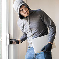 Hombre hurtando laptop de una casa